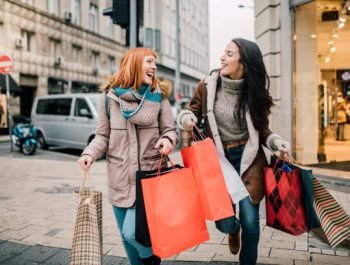 Happy two girls holding bunch of shopping bags
