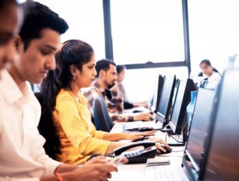 Outsourcing, Mumbai, Service - Group of call center executives seated in a row working on their desktop PC