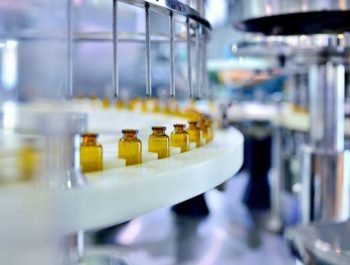 Cloes-up of brown glass bottle filling at production line.