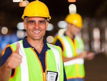 senior shipping company worker giving thumb up inside warehouse
